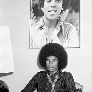 Michael Jackson poses beneath a photograph of his younger self in the 1970s.